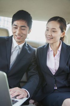 Business Colleagues Using Laptop in Back Seat Of Car