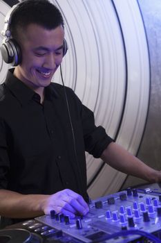 A portrait of a young male DJ playing music in a nightclub