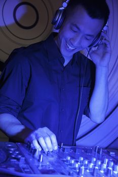 A portrait of a young male DJ playing music in a nightclub