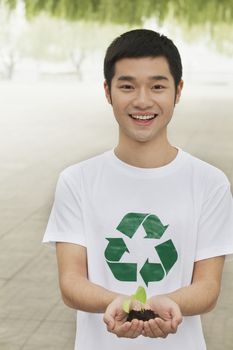 Young Man Holding Seedling in his Hands, Recycling Symbol, Beijing