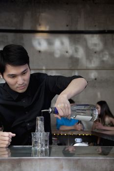 Bartender pouring licour on shot glass pyramid