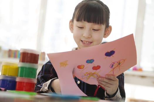 Schoolgirl cutting out drawing in class, Beijing 