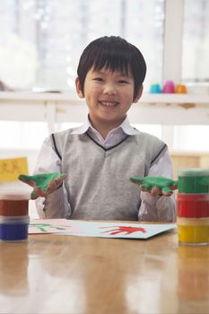 Portrait of smiling schoolboy finger painting in art class, Beijing