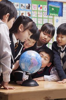 Schoolchildren looking at a globe in the classroom