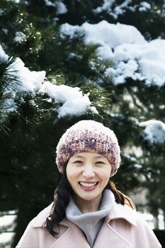 Smiling woman next to tree covered in snow, portrait