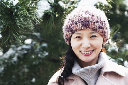 Smiling woman next to tree covered in snow, portrait