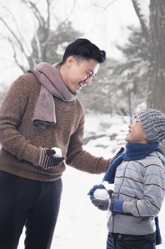 Father and son holding snowballs