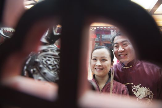 Couple holding offering incense at the temple in traditional clothing