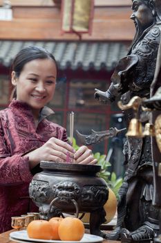 Woman offering incense, temple, Beijing