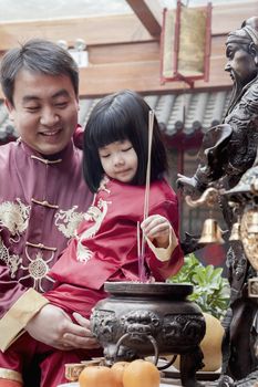 Father and daughter offering incense at the temple in Beijing