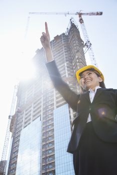 Young female architect pointing at a construction site