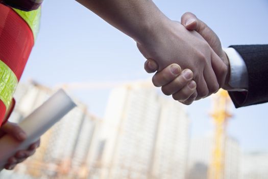 Close up of architect and building contractor shaking hands 