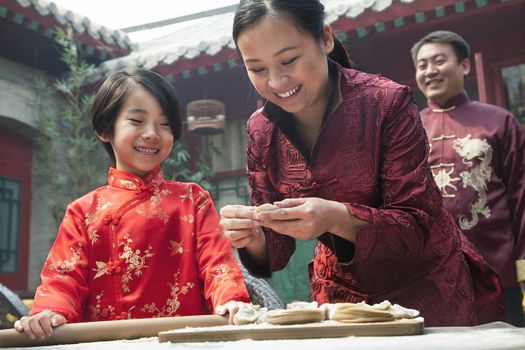 Mother and daughter making dumplings in traditional clothing