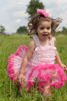 little girl in a pink dress runs on a grass