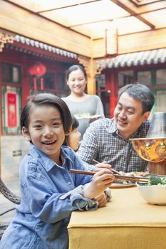 Portrait of little girl eating dinner with her family