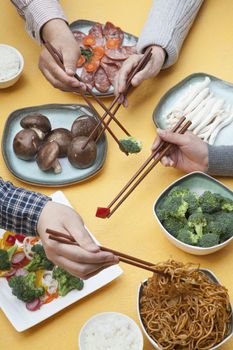 Close up of people using chopsticks with Chinese food