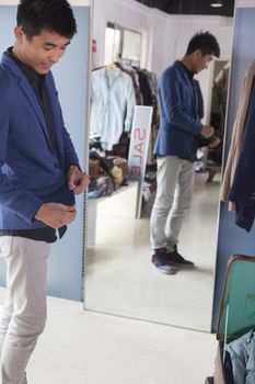 Young man trying on jacket at fashion store