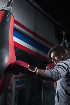 Determined boxer training at the gym on the punch bag 