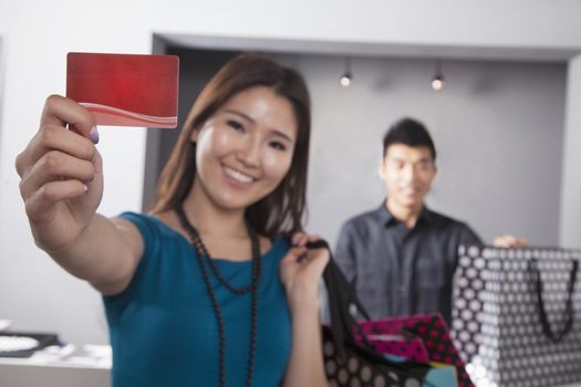 Young woman holding credit card at fashion store