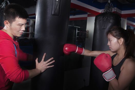 Boxing couch holding the punching bag and training a female student