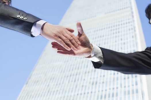 Close-up of two business people shaking hands by the World Trade Center in Beijing, China