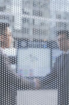 Two business people shaking hands seen through transparent glass