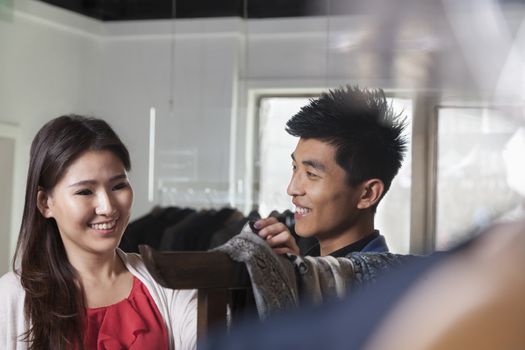 Store clerk showing scarfs to young woman at fashion store