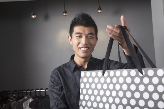 Store clerk holding shopping bag at fashion store