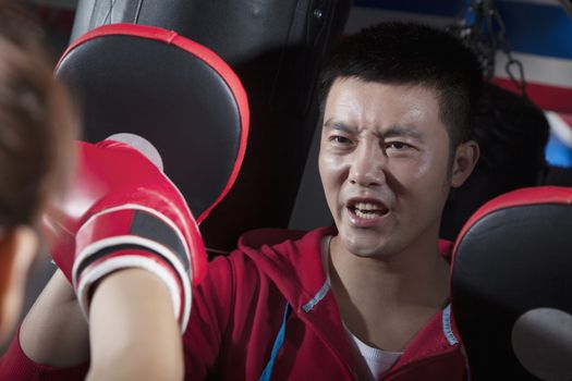 Boxing couch training with female student holding boxing pads