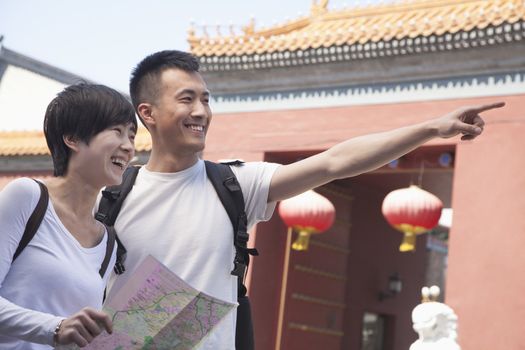 Young couple looking at map and pointing. 