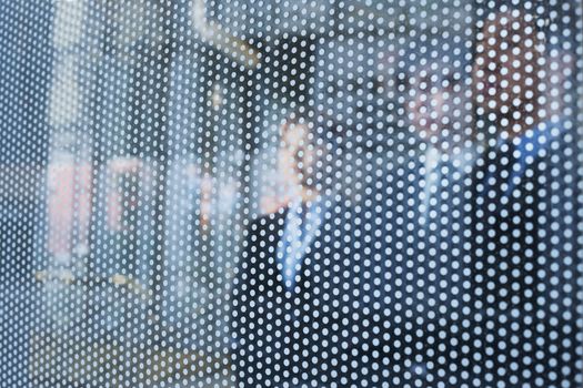 Three business people behind a glass wall looking out, unrecognizable faces