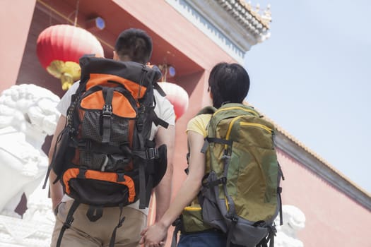 Young couple with backpacks, holding hands. 