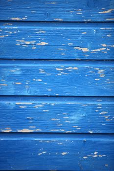 Background texture of blue painted wooden planks with weathered peeling paint used as a building material and cladding in construction with rough woodgrain pattern