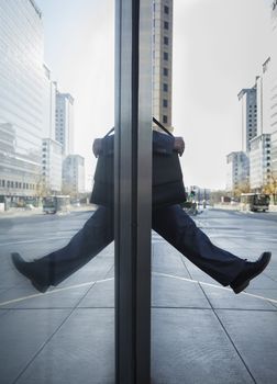 Businessman stepping out into the street, reflection in the glass of the building