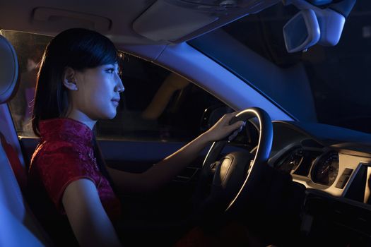 Young beautiful woman in a traditional Chinese dress driving at night  