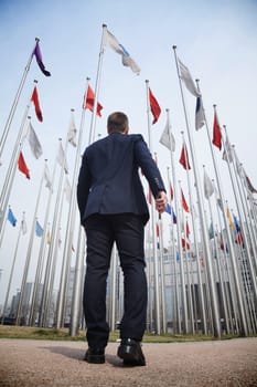 Rear view of businessman walking towards many flying flags