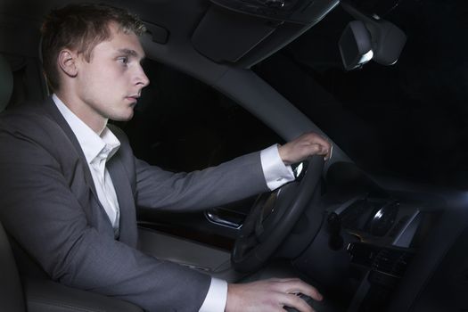 Young well-dressed man in a suit is sitting in his car before going on a night out in Beijing