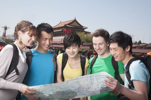 Five people looking at map with Tiananmen Square in background.