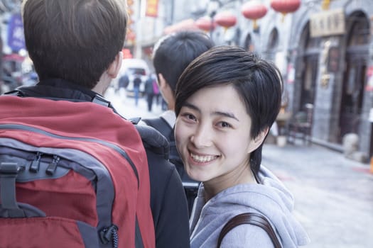 Young couple walking down street, woman looking over shoulder.