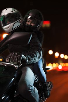 Young couple riding a motorcycle through the city streets at night in Beijing