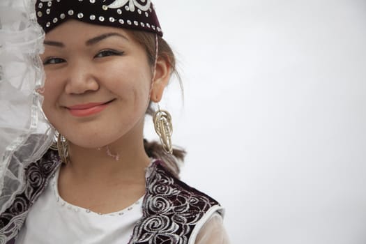 Portrait of young smiling woman in traditional clothing from Kazakhstan, studio shot