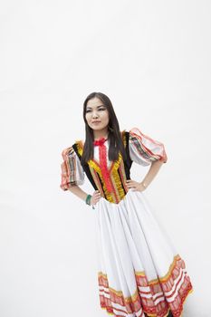 Portrait of young smiling woman with hands on hips in traditional clothing, studio shot