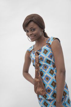 Portrait of young smiling woman with hand on her hip in traditional dress from Africa, studio shot