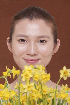 Portrait of smiling young woman behind a bunch of yellow flowers, studio shots