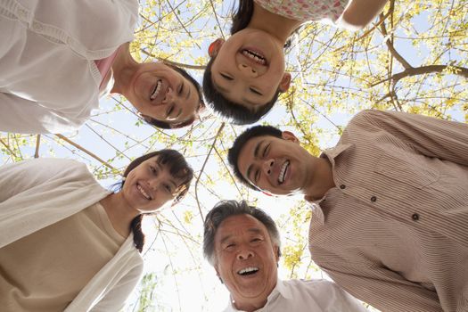 Happy smiling family in a circle looking down in a park in the springtime