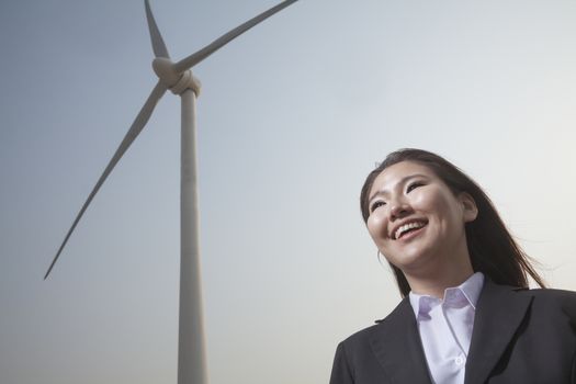 Portrait of smiling young businesswoman standing by a wind turbine