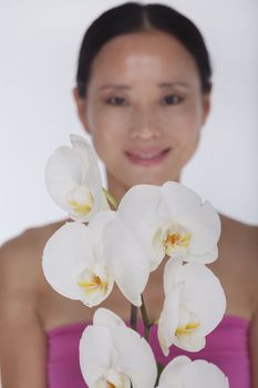 Smiling woman standing behind a bunch of beautiful  white flowers, studio shot