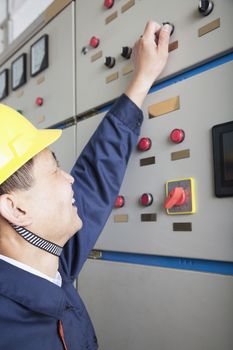 Smiling worker checking controls in a gas plant, Beijing, China