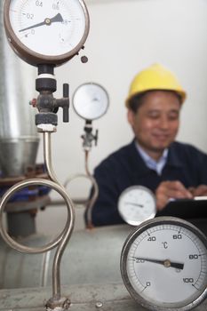 Close- up on gas gauges with worker in the background in a gas plant, Beijing, China 