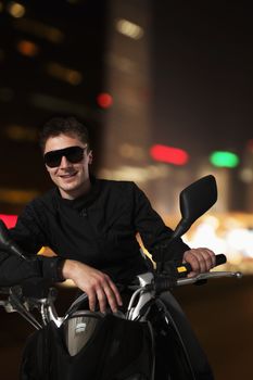 Young smiling man in sunglasses sitting on his motorcycle at night in Beijing